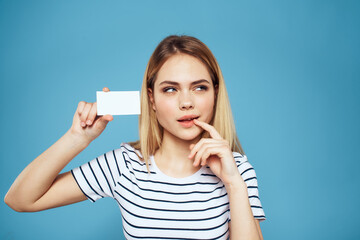 Woman with a business card in her hands a striped T-shirt blue background Copy Space