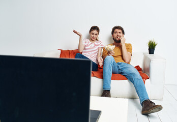 Man and woman on sofa with flower room interior and TV screen