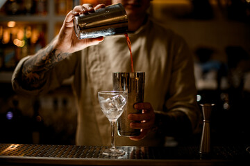Bartender pouring cocktail from one glass into another glass.