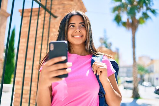 Young latin student girl smiling happy using smartphone at university campus.