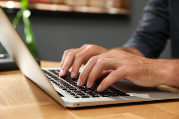 Man using laptop for search at wooden table indoors, closeup