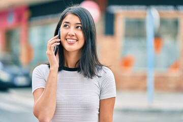 Fototapeta premium Young hispanic woman smiling happy talking on the smartphone at the city.