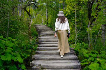 Young woman traveler walking on wooden path trail in Plitvice Lakes National Park, UNESCO natural world heritage and famous travel destination of Croatia