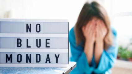White board with text no blue monday on the table, in the background a woman in blue clothes depressed near the window,defocused.Blue monday day banner concept. Lettering.