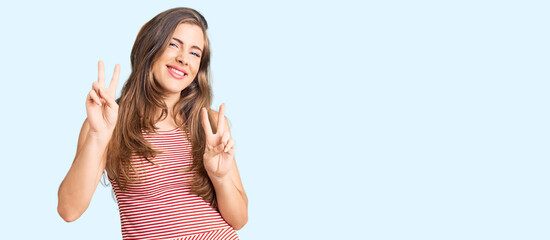Fototapeta na wymiar Beautiful caucasian young woman wearing casual clothes smiling looking to the camera showing fingers doing victory sign. number two.