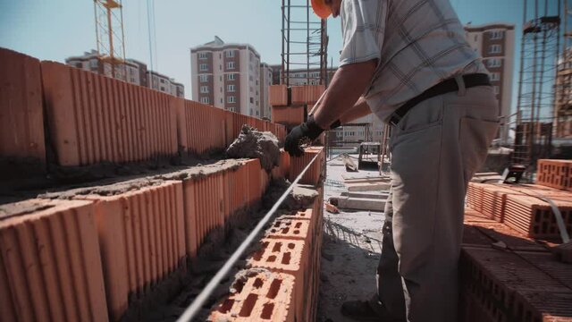 Fast close up trough the wall to a builder who place a bricks