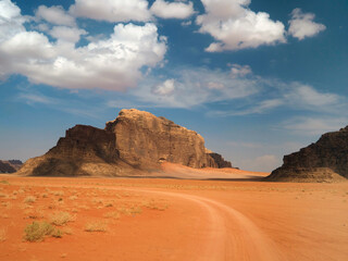 Fototapeta na wymiar Wadi Rum characteristic landscape: rocky valley and 4x4 car tracks on the orange sand