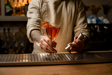 cocktail glass with splashing alcoholic drink in male barman hand
