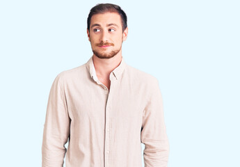 Fototapeta premium Young handsome caucasian man wearing casual clothes smiling looking to the side and staring away thinking.