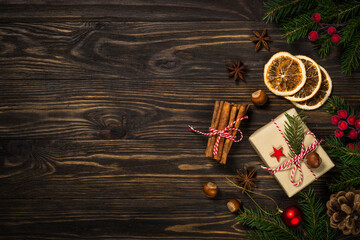 Christmas background with fir tree, present box and spices at wooden table.