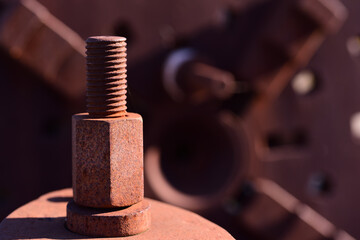 Obraz na płótnie Canvas Close up of a rusty nut and threaded bolt standing in front of a rusty metal machine