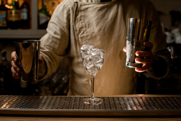 Transparent wine glass full of ice cubes stands on the bar counter.