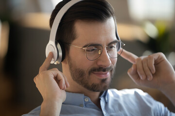 Close up image guy wear wireless headphones listen audio course improve english knowledge using online lesson, enjoy music relaxing at work. Hobby, modern technology usage for fun or learning concept
