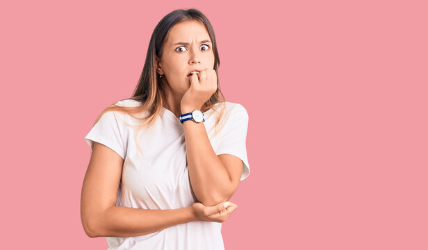Beautiful caucasian woman wearing casual white tshirt looking stressed and nervous with hands on mouth biting nails. anxiety problem.