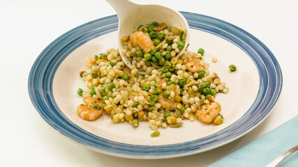 Serving delicious food. Pan-fried shrimp and blend of couscous, orzo, garbanzo beans, red quinoa, andgreen peas