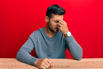 Handsome hispanic man wearing casual style sitting on the table tired rubbing nose and eyes feeling...