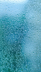 Drops of rain on window glass. Shallow DOF. Natural Blue Water background with Raindrops for sad mood and thoughts. Selective focus