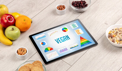 Organic food and tablet pc showing VEGAN inscription, healthy nutrition composition
