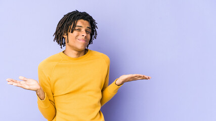 Young black man wearing rasta hairstyle doubting and shrugging shoulders in questioning gesture.
