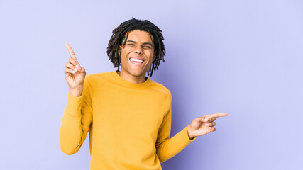 Young black man wearing rasta hairstyle pointing to different copy spaces, choosing one of them,...