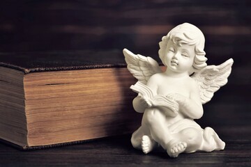 Guardian angel and book on dark background