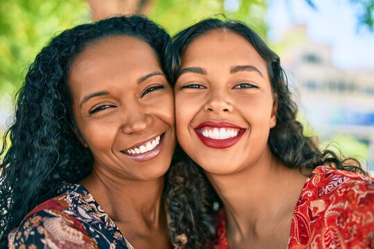 African american mother and daughter smiling happy hugging at the park.