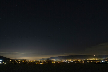 Night view of the starry sky with a city on the horizon