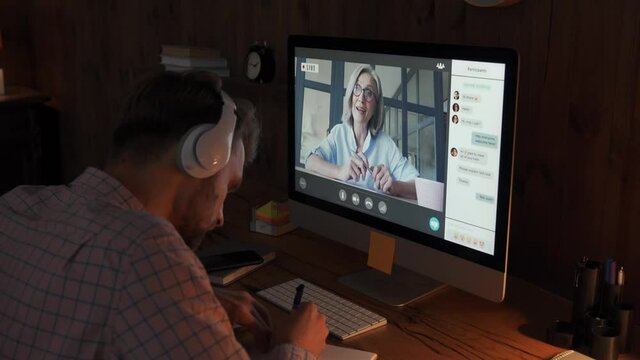 Male student wears headphones conference video calling, watching webinar stream, taking online training class virtual chat meeting with remote teacher, tutor or coach distance learning using computer.