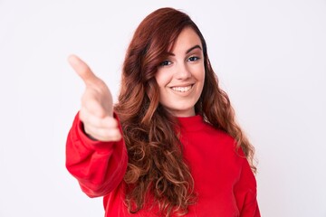 Young beautiful woman wearing casual clothes smiling friendly offering handshake as greeting and welcoming. successful business.