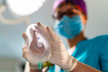 Oxygen mask from the eyes of a patient. Female anesthesiologist in scrubs putting anesthetic mask...