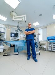 Portrait of the professional surgeon looking into camera and smiling after successful operation. In the background modern hospital operating room.