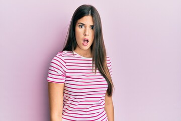 Young brunette woman wearing casual clothes over pink background in shock face, looking skeptical and sarcastic, surprised with open mouth