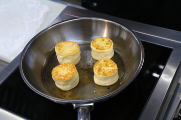 cooking cottage cheese pancakes in a skillet in the kitchen