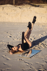 Fototapeta na wymiar Beautiful young sexy woman in black body beachwear on the sand 