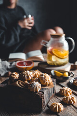 Woman is reading and Hot tea with fresh grapefruit on wooden tablet. Healthy drink, Eco, vegan.