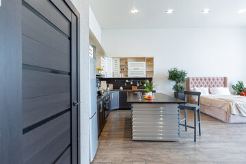 Contemporary ordinary design of spacious studio in soft warm colors. Simple furniture. Light large room with sunlight. Daytime. Tiled brown floor and white walls .