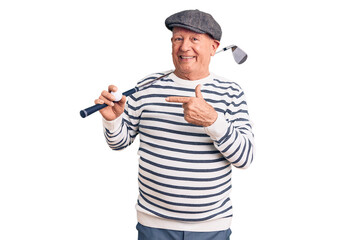 Senior handsome grey-haired man holding golf club and ball smiling happy pointing with hand and finger
