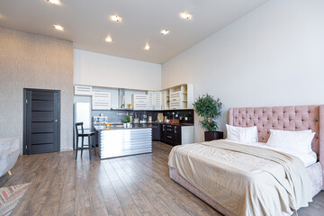 Contemporary ordinary design of spacious studio in soft warm colors. Simple furniture. Light large room with sunlight. Daytime. Tiled brown floor and white walls .
