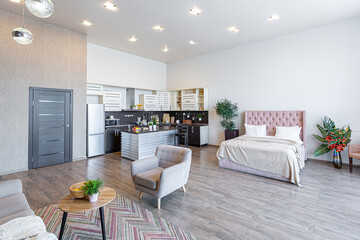 Contemporary ordinary design of spacious studio in soft warm colors. Simple furniture. Light large room with sunlight. Daytime. Tiled brown floor and white walls .