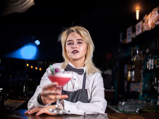 Young girl bartender demonstrates the process of making a cocktail