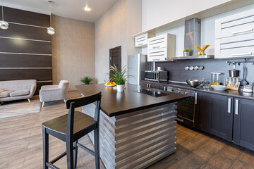 Contemporary ordinary design of spacious studio in soft warm colors. Simple furniture. Light large room with sunlight. Daytime. Tiled brown floor and white walls .
