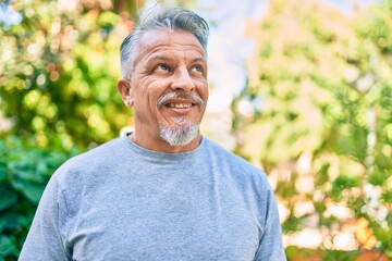 Middle age hispanic grey-haired man smiling happy standing at the park.