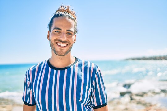 Young hispanic man smiling happy looking to the camera at city.