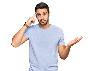Young hispanic man wearing casual clothes confused and annoyed with open palm showing copy space...