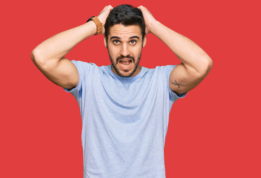 Young hispanic man wearing casual clothes crazy and scared with hands on head, afraid and surprised of shock with open mouth