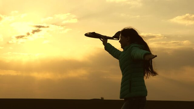 girl wants to become pilot and an astronaut. Free girl runs with a toy airplane on field in sunset light. healthy children play toy airplane. teenager dreams of flying and becoming pilot. Slow motion