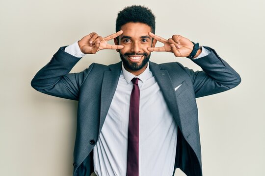 Handsome young hispanic man wearing business suit and tie amazed and smiling to the camera while presenting with hand and pointing with finger.