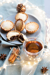 spiced black tea and sweet mince pies on a table with Christmas decoration, cinnamon sticks and anise stars. - 392729356