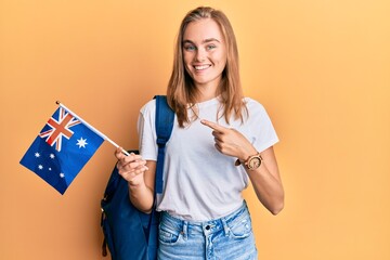 Beautiful blonde woman exchange student holding australia flag smiling happy pointing with hand and...