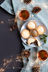mince pies on a plate and cups with black tea shot from above with copy space. A mince pie is a traditional Christmas sweet pie, filled with a mixture of dried fruits and spices